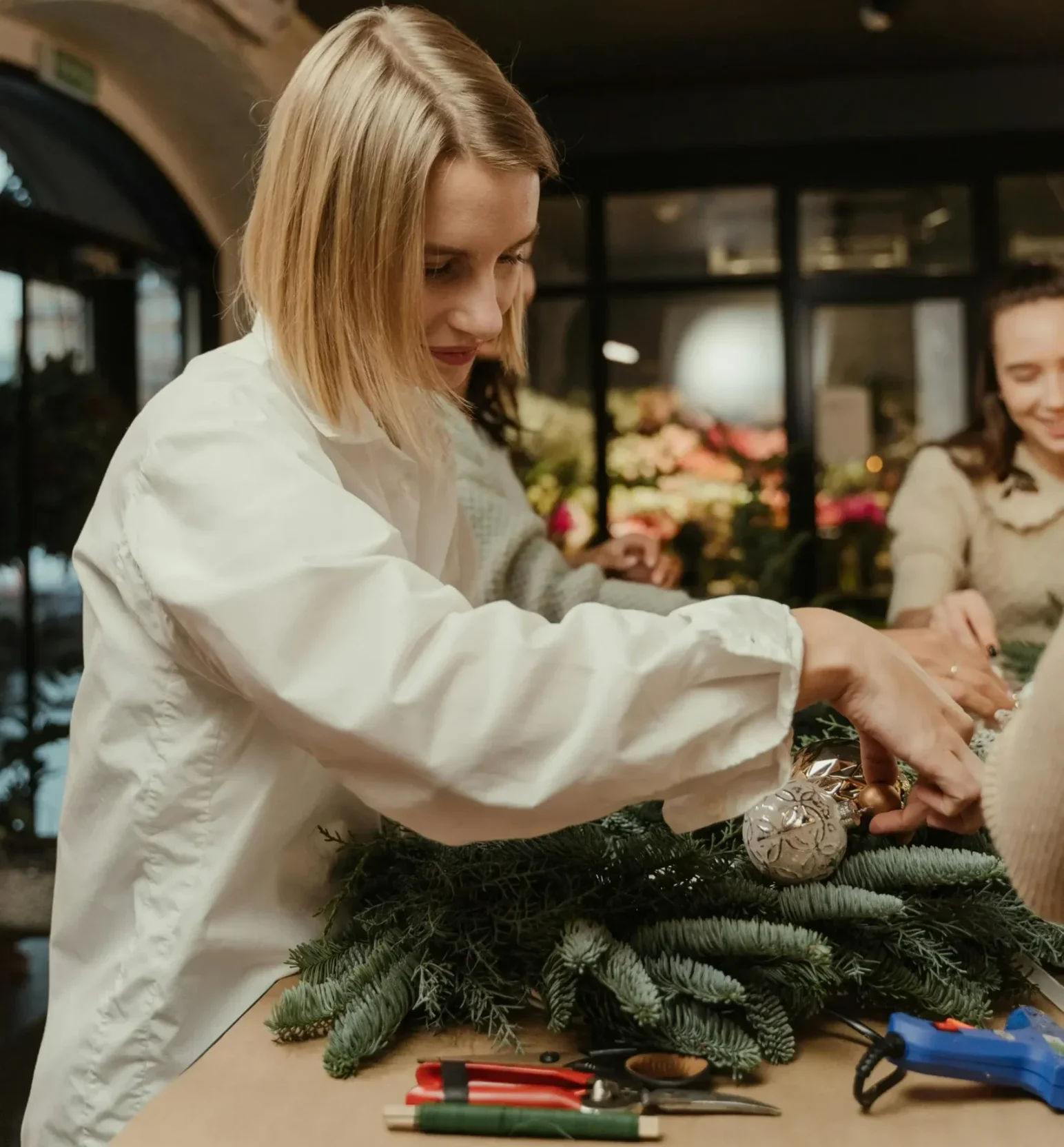 Warsztaty świąteczne dla firm. Zdobienie stroików. Zdjęcie kobiety która wykonuje stroik świąteczny.